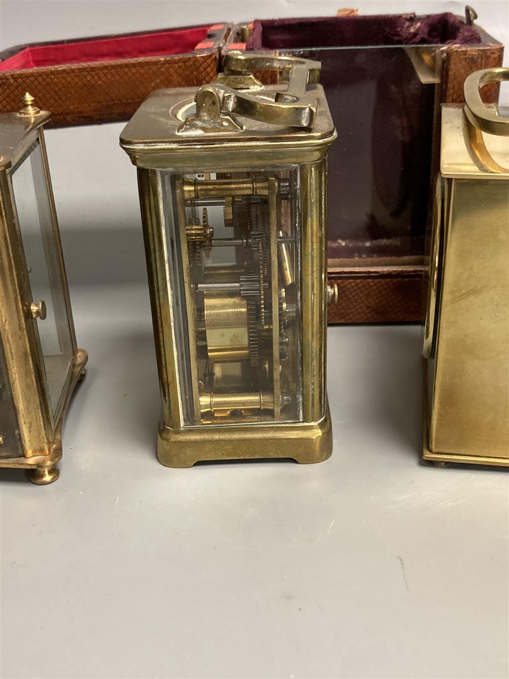 Three small gilt brass carriage timepieces, one with leather outer case, largest 10.5cm high